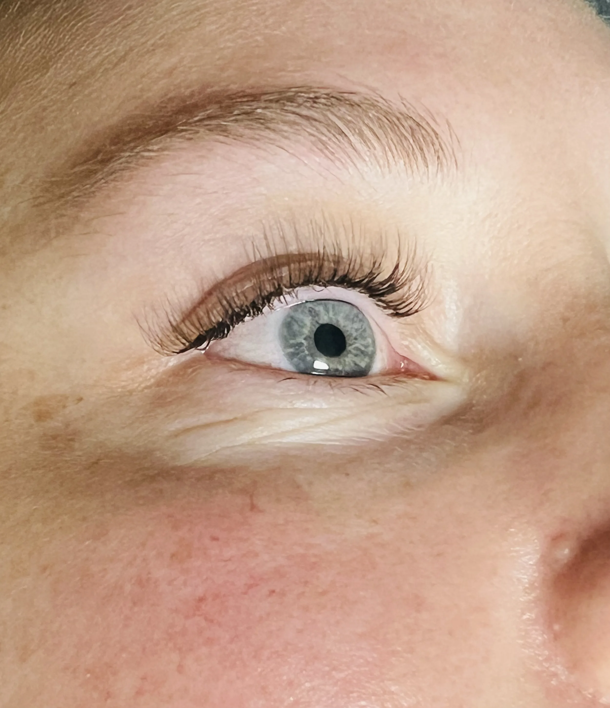 Clean classic lash extension set — blue-grey eye, side profile, natural length and volume
