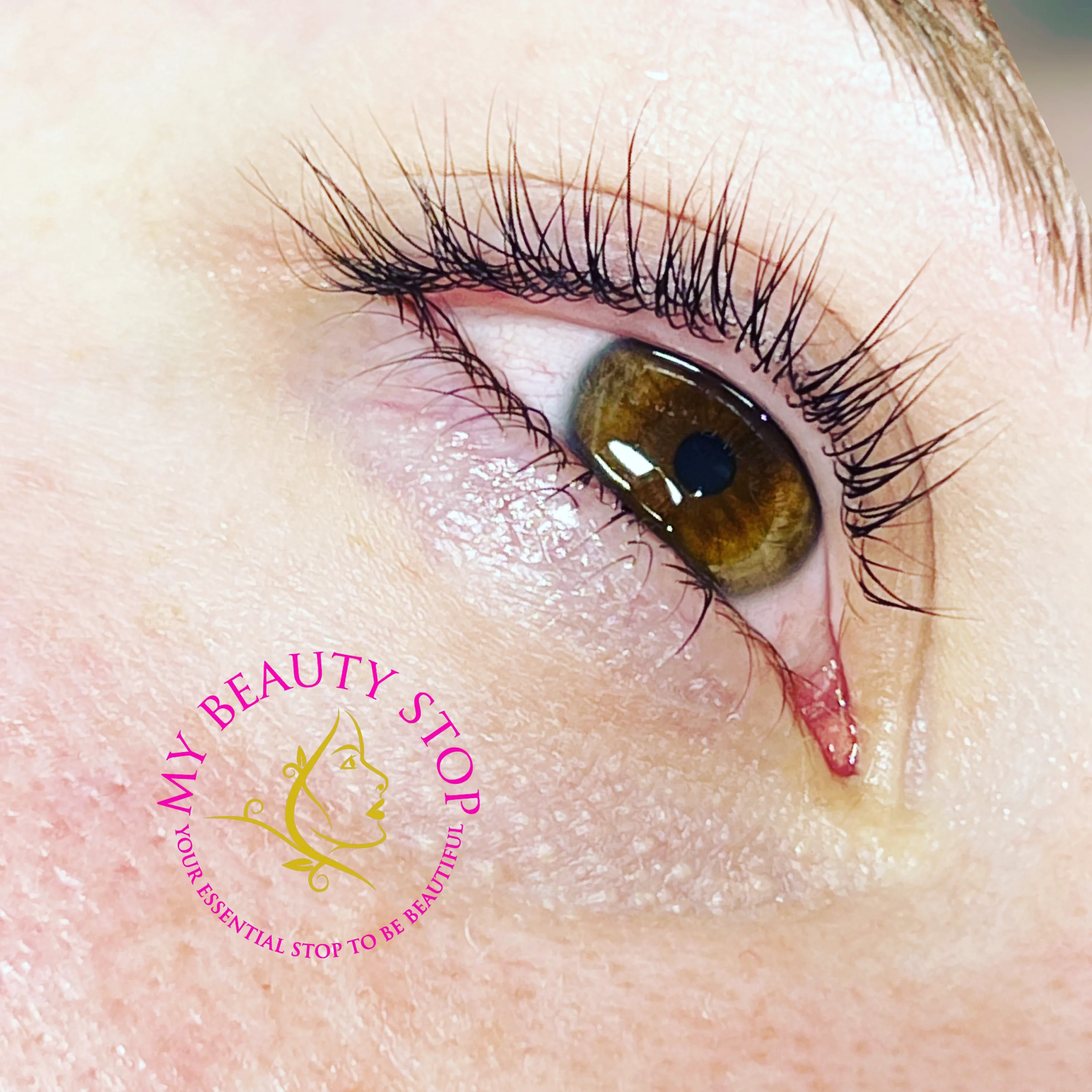 Lash lift result — hazel eye macro with the circular My Beauty Stop logo watermark, showing the curl and lift of natural lashes
